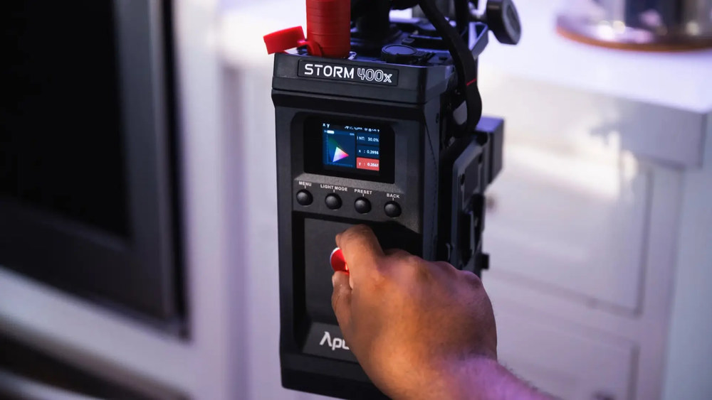 Блок питания Aputure Storm 400x с дисплеем и кнопками управления — рука регулирует настройки через красный джойстик